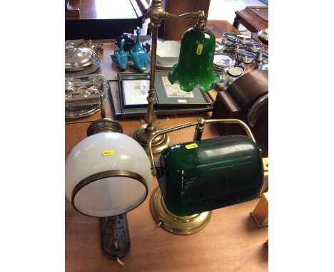 Two brass desk lamps with green glass shades and one other wall light