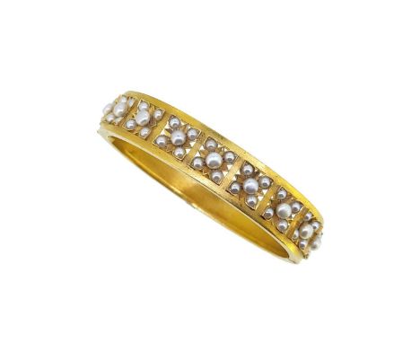 A cased early 20th century pearl set hinged bangle, nine pierced sections, each with a flower set with pearls, plain back sec