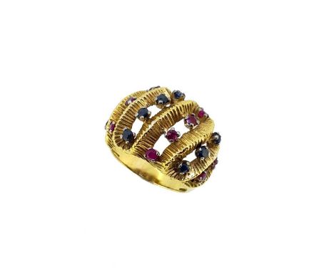 A sapphire and ruby bombé style dress ring, pierced and textured head with alternate rows of claw set round faceted rubies an