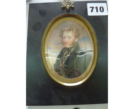 An early 19th century miniature portrait of oval form showing a stylish gentleman with curly red hair and side whiskers, wear