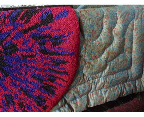 A vintage feather filled bedspread with paisley patterned colourway, a 1970s splash rug of circular form with red and turquoi