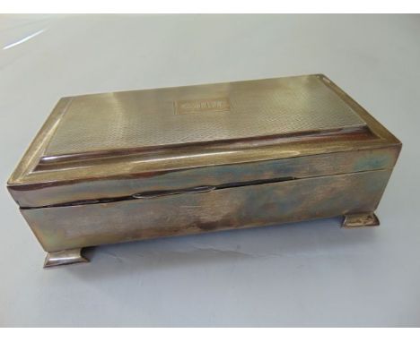 A sterling silver cigar box, indecipherable marks, the rectangular body on four bracket feet, the hinged cover with engine tu