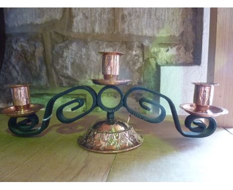 A tri sectional copper candelabra, each font with chased foliate detail with a flared rim, set above shallow beaten dishes, a
