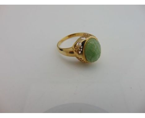 A Chinese ring, centred with an oval carved jade motif, with pierced gallery, in 14ct gold, size U