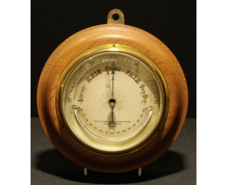 A late 19th/early 20th century circular aneroid barometer, the dial with crescent shaped thermometer, oak cased, The Goldsmit