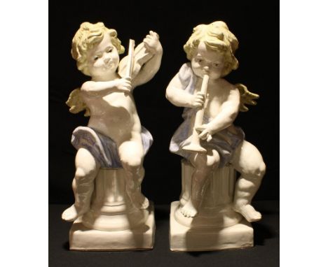A pair of decorative ceramic cherubs, playing musical instruments, scantily clad, seated on fluted pedestals, crackle glazed,