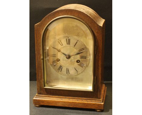 An early 20th century oak bracket clock, 13.5cm arched silvered dial, the chapter ring inscribed with Roman numerals, twin wi