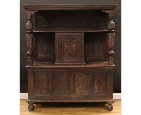 A late Victorian oak duodarn or side cabinet, in the 17th century taste, outswept cornice above a shelf and a panel door carv