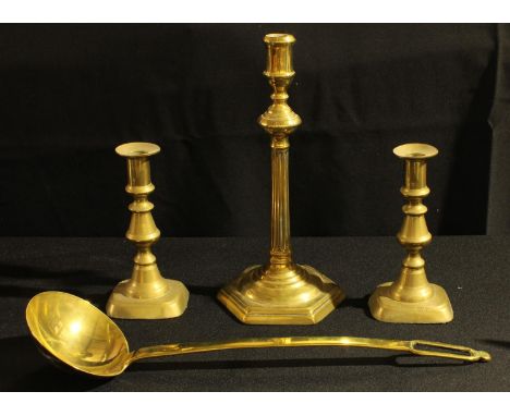 A George III brass candlestick; another pair, Victorian; a large brass ladle (4) 