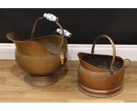 A brass helmet shaped coal scuttle with Delft blue ceramic handles; a copper coal scuttle (2) 