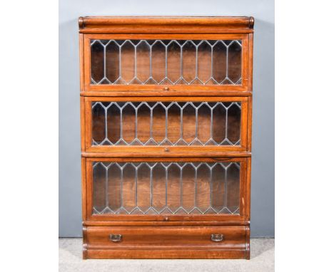 A Globe Wernicke Oak Three Tier Sectional Bookcase, each section enclosed by a leaded glazed rising front, on plinth base fit