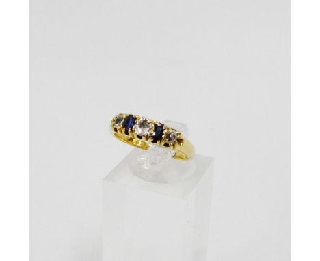 A diamond and sapphire five stone ring, claw set on a yellow metal band UK ring size M