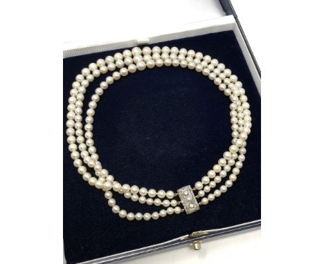 An antique triple strand pearl necklace with diamond set clasp