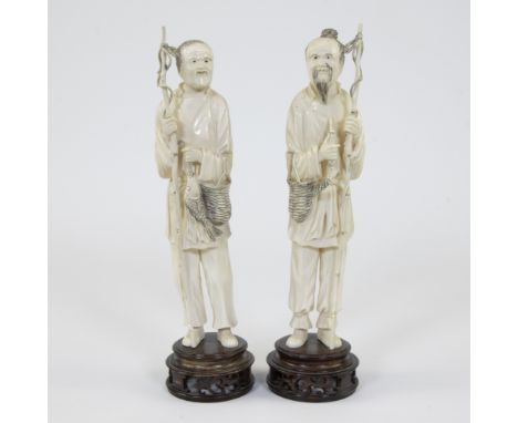 A pair of ivory Japanese okimono depicting two almost bald-headed old fisherman, both hold their fishing rod in one hand and 