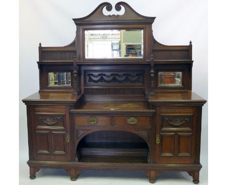 A large and imposing late Victorian oak mirror backed sideboardThe upper section featuring a scrolling crest above bevelled m