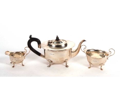 A three piece silver tea service comprising of a silver teapot of oval form, ebonised handle, having a wavy rim and supported