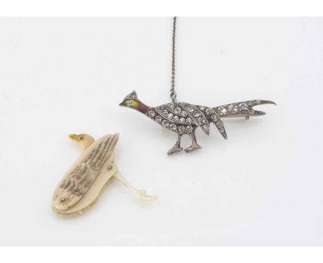 A silver enamel and paste set white metal pheasant brooch, 4.3 cm by 1.5 cm, together with a bone toy game bird, with moving 