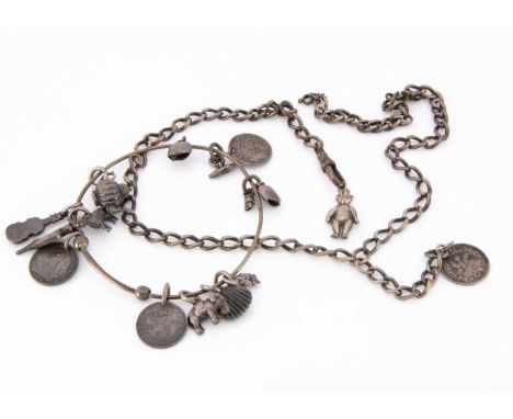 An Edwardian white metal bangle, with a collection of charms including a tea pot, fire bellows, three coins, violin and other