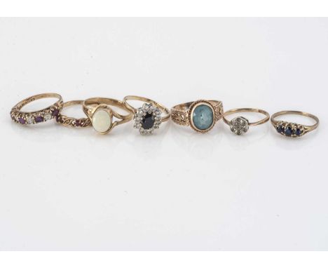 A collection of seven 9ct gold gem set rings, including a topaz single stone, a ruby and CZ, white opal, sapphire and others 