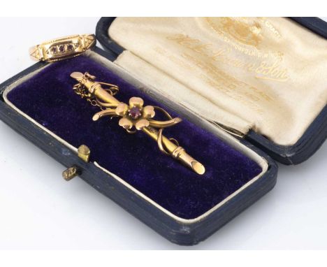 A 15ct gold bar brooch, centred with a flower design, 4.5cm, boxed, together with a 15ct gold three stone ruby dress ring, ri