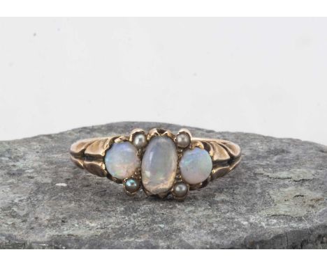 An Edwardian three stone opal and seed pearl dress ring, the cabochons centred with an oval flanked by two round examples, wi