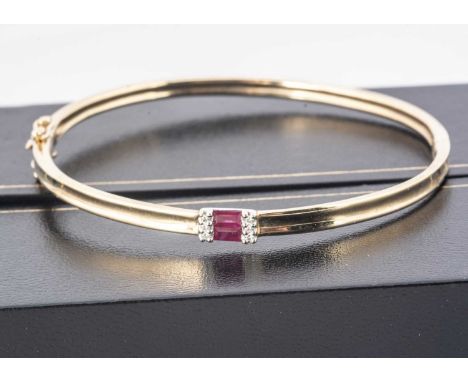 A 9ct gold ruby and diamond bangle, centred with a pair of step cut rubies, flanked by three brilliant cut diamonds to each e