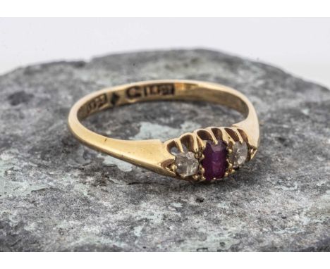 An 18ct gold three stone ruby and diamond dress ring, the mixed cut rectagular ruby, flanked by two old cuts, all set with cl