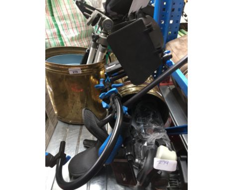 2 brass stick stands containing camera tripods and a shoulder camera holder