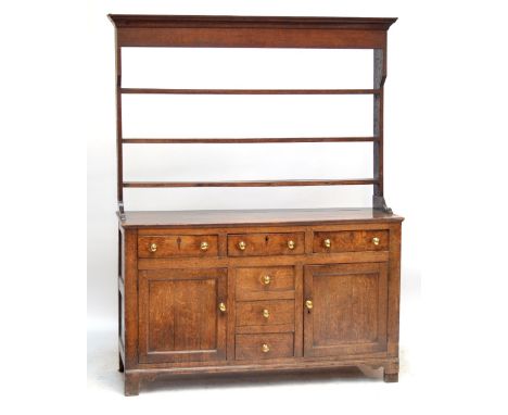 An early 19th century oak North Walian dresser, with open plate rack above base and T-formation of drawers, twin cupboard doo