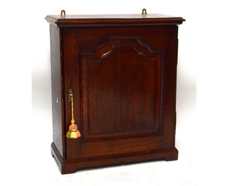 An 18th century oak table top or side cabinet with single fielded panel door enclosing a central aperture and eight small dra