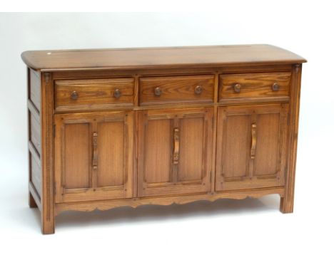 ERCOL; a sideboard of three drawers above two compartments, each enclosing single shelf, width 146cm.