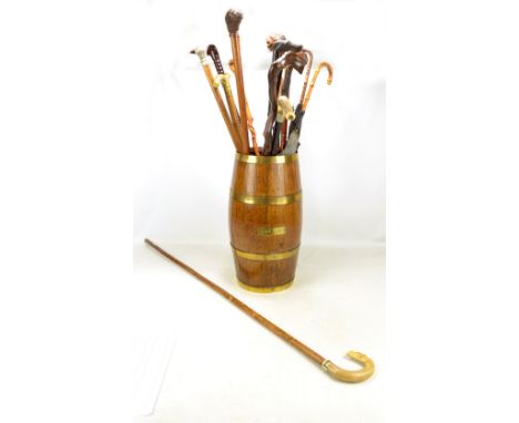 An early 20th century oak coopered barrel form stick stand with a quantity of walking sticks, umbrellas and a shepherd's croo