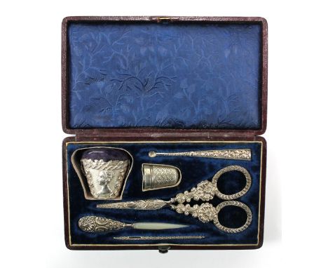 A cased Victorian white and base metal sewing set including a bucket shaped pin cushion decorated with bust of a young female