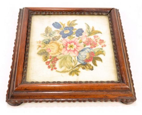 A Victorian rosewood tea board with central glazed needlework floral decorated panel, moulded frame and four squat turned fee