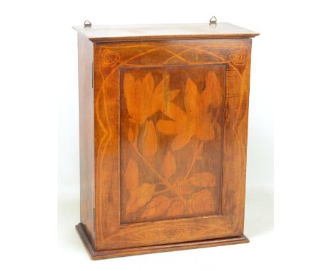 An Edwardian stained beech and stencil decorated wall cabinet, the hinged door with stylised Art Nouveau floral detail reveal