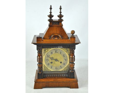 A circa 1900 German oak cased mantel clock with caddy top above brass base with circular dial, height 48cm including turned f