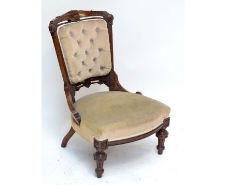 A Victorian walnut button upholstered nursing chair raised on turned fluted front legs.