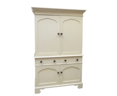 A cream painted pine side cabinet, the moulded cornice above an upper section with two arched panel doors and with base of tw