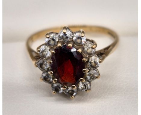 Birmingham 9ct yellow gold ring fitted with an oval cut garnet gem stone surrounded by CZ Stones. [Ring size O] [2.31Grams] 