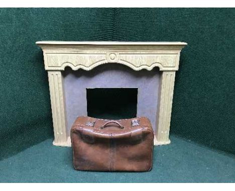 A light oak fire surround and a leather suit case 