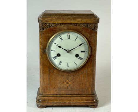 An early 20th century inlaid oak cased mantel clock, the convexed enamel dial with Roman numerals, housing an 8 day movement 