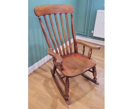 A 20th century light beech Windsor style rocking chair, with overhanging comb top, serpentine pierced back splat, shaped arms