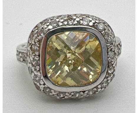 A silver, lemon quartz and cubic zirconia cocktail ring with central cushion cut stone. Surrounded by a halo of cubic zirconi