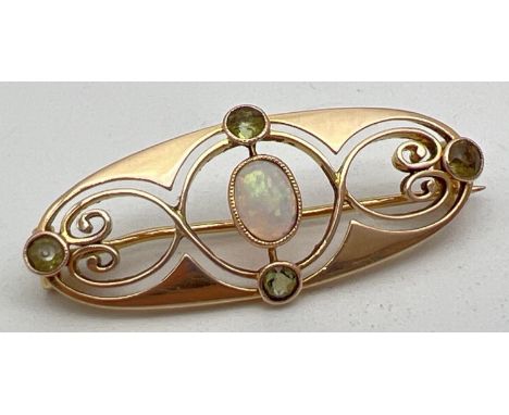A Merrle Bennet Art Nouveau 15ct gold brooch set with central oval cut opal and 4 small round cut peridots. Stamped 15ct to r