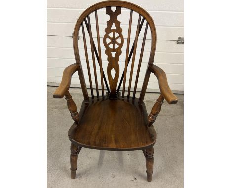 A vintage wheel backed elm wood Windsor armchair with spindled back and turned legs and arm supports. 
