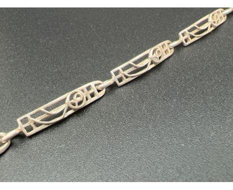 A silver 7 panel pierced work Rennie Mackintosh style bracelet with rose design. Approx. 8 inches long with spring ring clasp