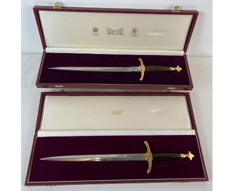 2 boxed Wilkinson Sword presentation Daggers, with wood effect handles and brass fixings. Wilkinson sword name to both blades