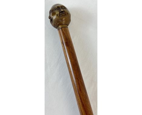 A modern wooden walking stick with brass handle modelled as the four faces of Buddha. Approx. 92.5cm long. 