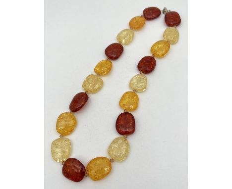 An 18" multi coloured amber beaded necklace with spring ring clasp. Of alternating cognac, honey and lemon amber beads. Total