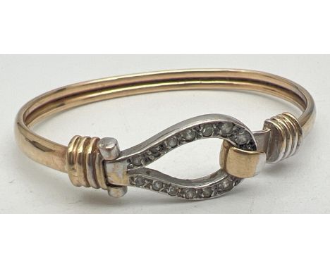 A yellow and white 9ct gold child's bangle with clear stone set hook and eye clasp. Gold marks to underside of clasp. Approx.